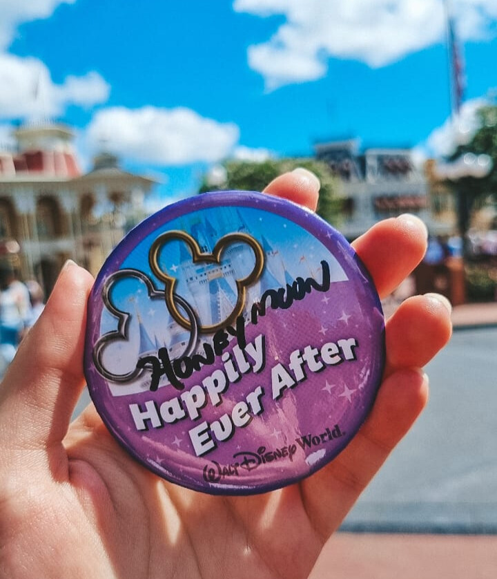botton-disney-happily-honeymoon Botton de comemoração 'Happily Ever After' da Disney personalizado com a palavra 'Honeymoon', símbolo da celebração da lua de mel nos parques