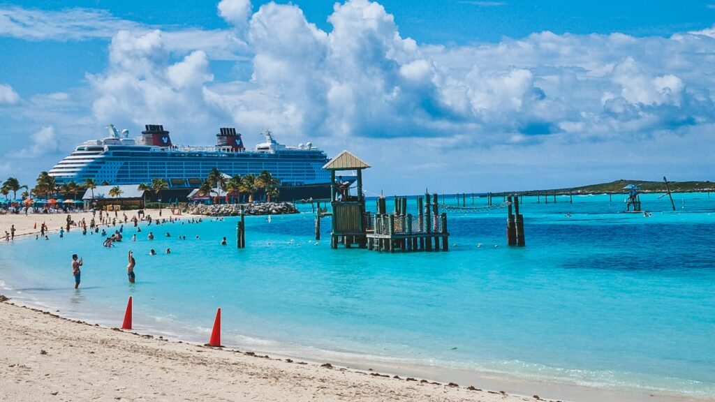 castaway-cay-beach-disney-cruise Navio Disney Dream ancorado em Castaway Cay, visto da praia com águas cristalinas e cadeiras à beira-mar