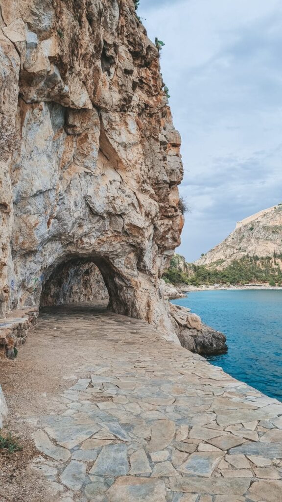 rilha costeira da Arvanitia Promenade em Nafplio com mar azul ao lado e paredões rochosos ao fundo
